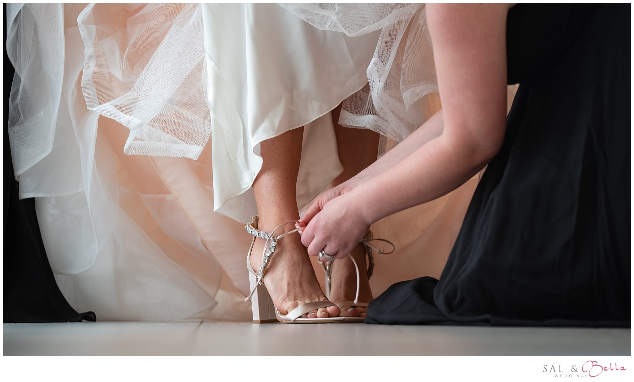 bridesmaid ties the brides shoe.