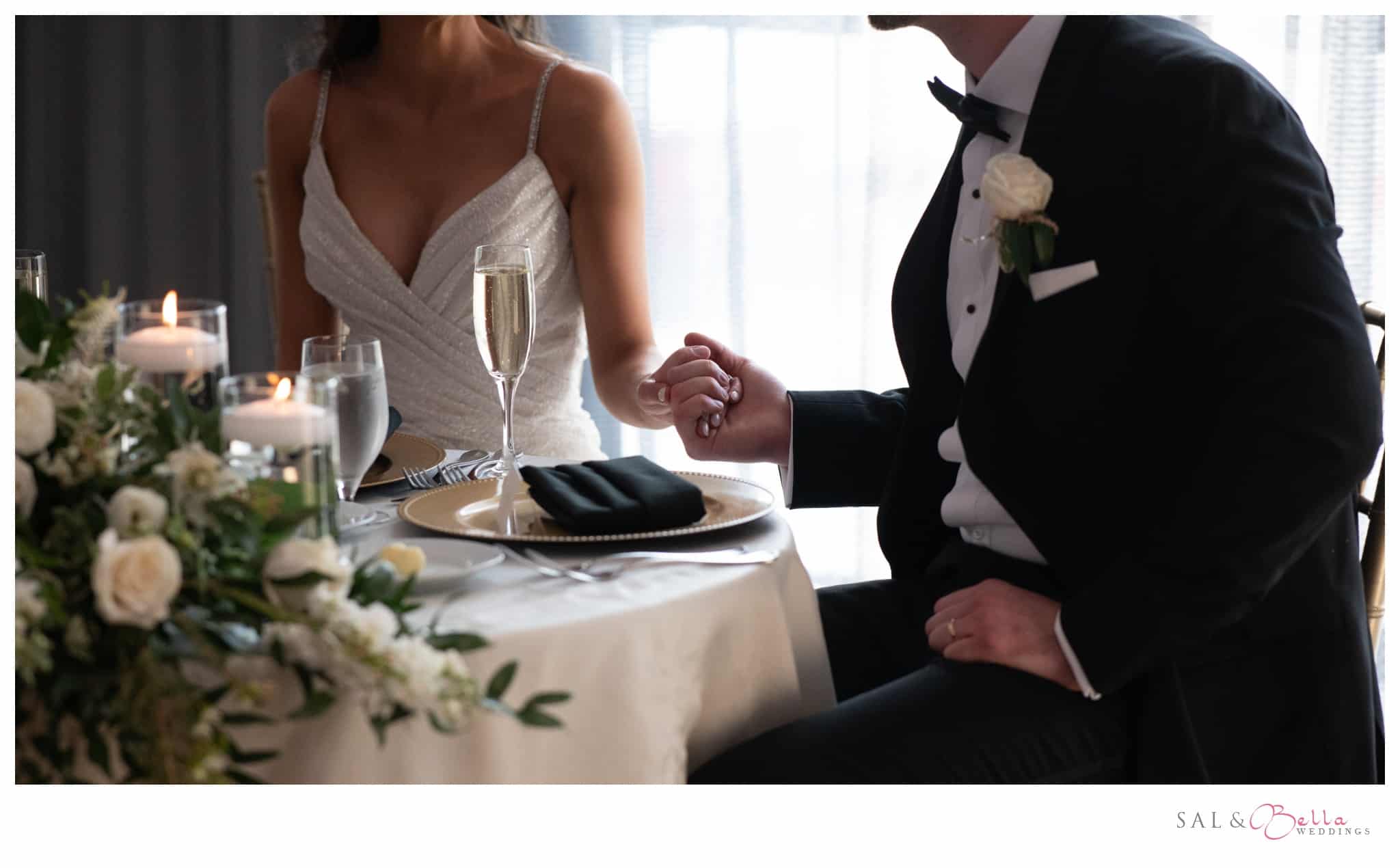 couple holds hands while sitting at their sweetheart table at the Renaissance Pittsburgh Hotel