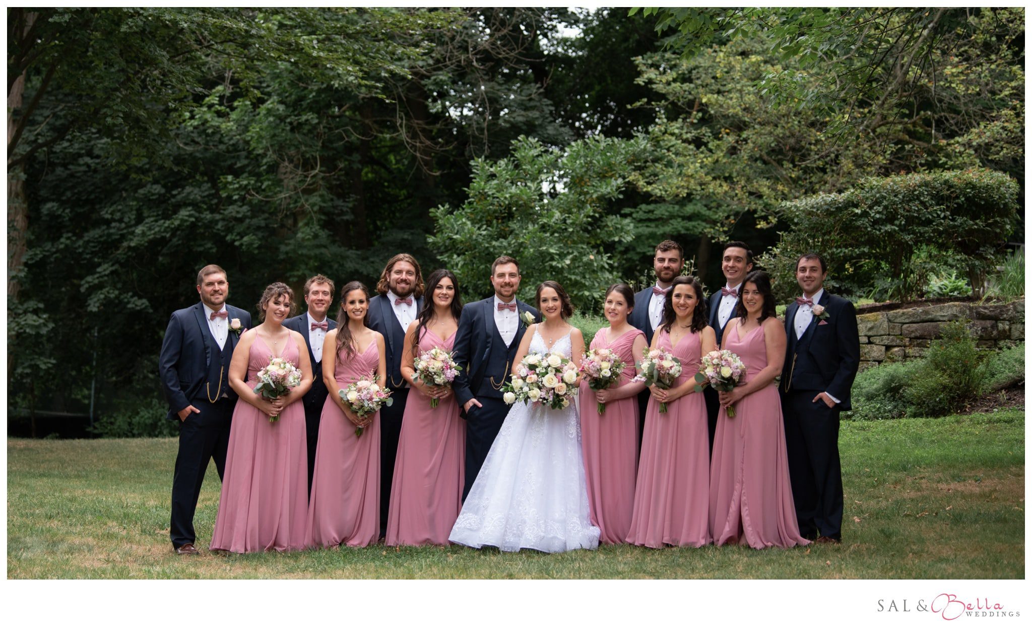 wedding party poses for photos in the park.