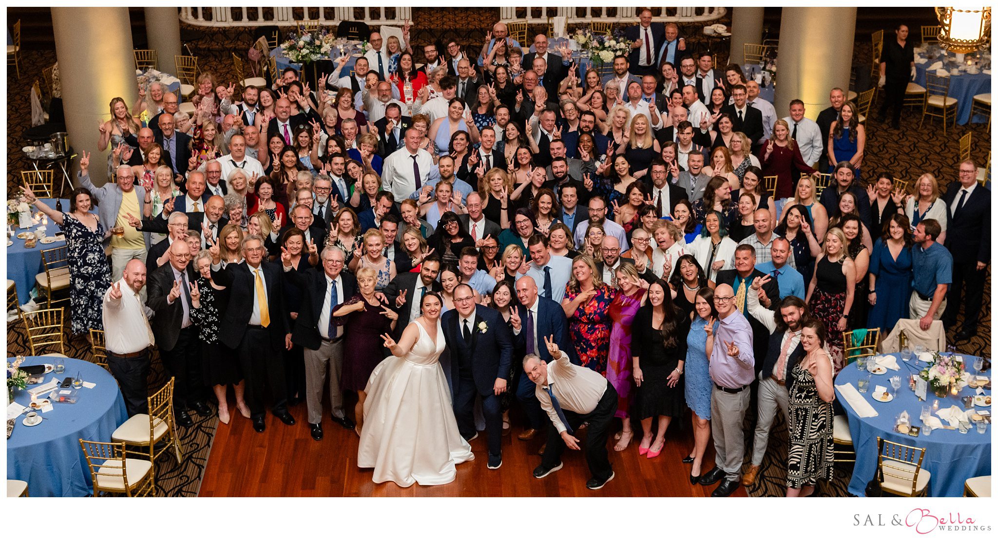 Wedding guests gather on the dance floor for a group photo at the Priory's Grand Hall.