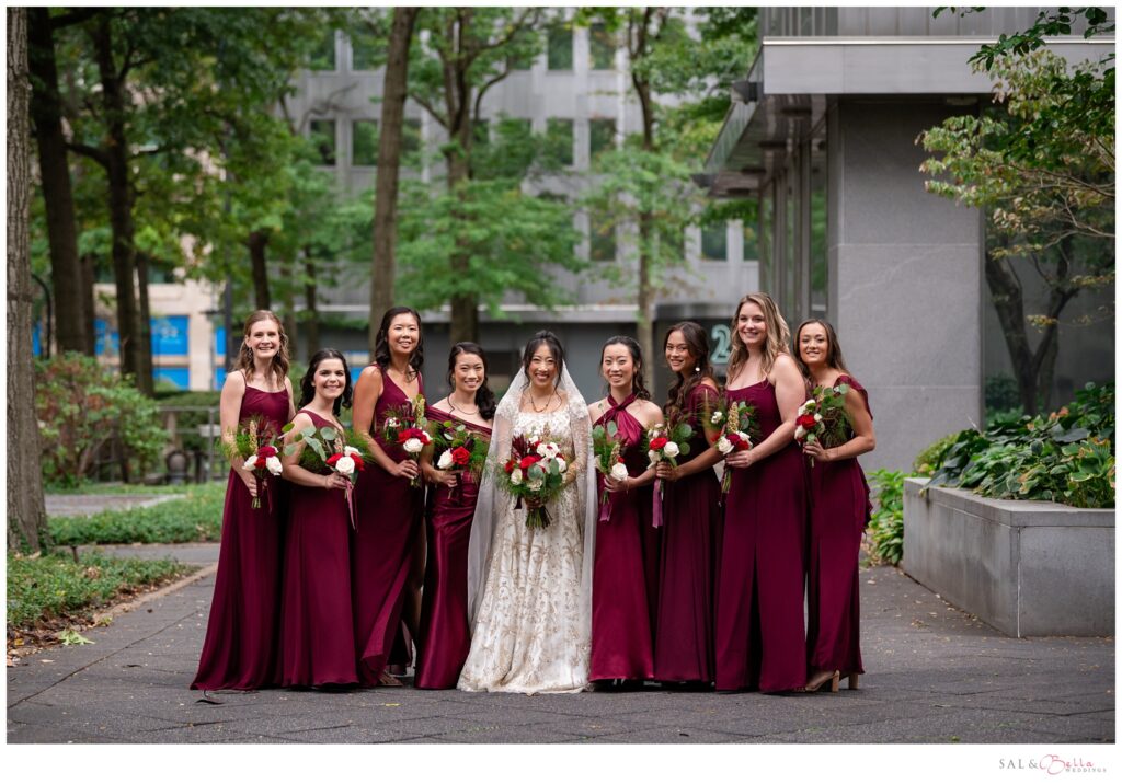 Bridesmaids in burgundy dresses pose alongside the bride.