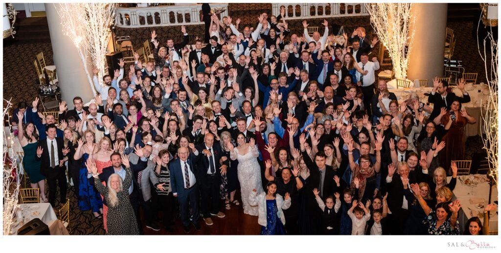 Group photo of all wedding guests taken from the balcony at The Priory Grand Hall