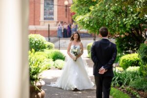 Bride walks to her groom as they share a first look in the garden of the Priory