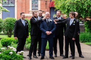 Groomsmen joke with the groom to be as the priory sits in the background.