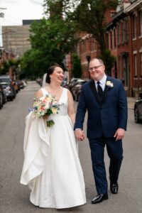 A couple walks hand in hand down the street on the northside out in front of the Priory.