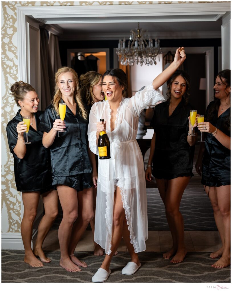 Elle celebrating with her bridesmaids and popping a bottle of Prosecco while getting ready for her Pittsburgh wedding