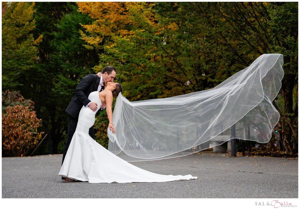 wedding portrait of Elle and Mike kissing with her veil blowing in the wind at Mellon Green in Pittsburgh