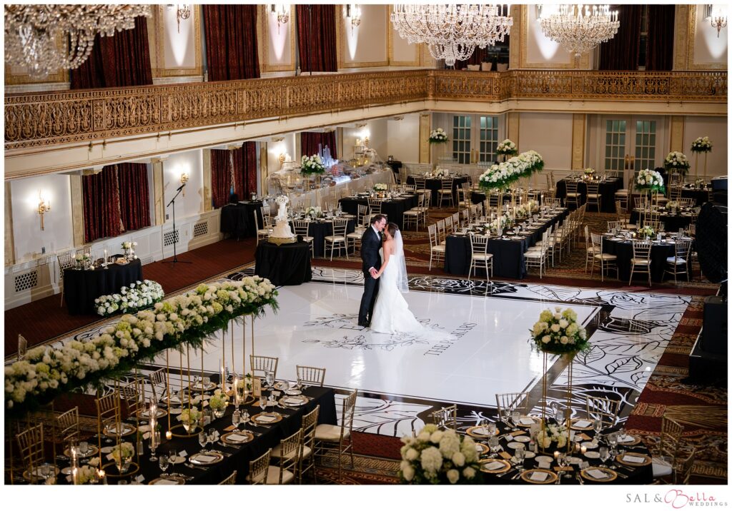 Bride and groom together on the dance floor surrounded by their elegant Omni William Penn Grand Ballroom wedding reception